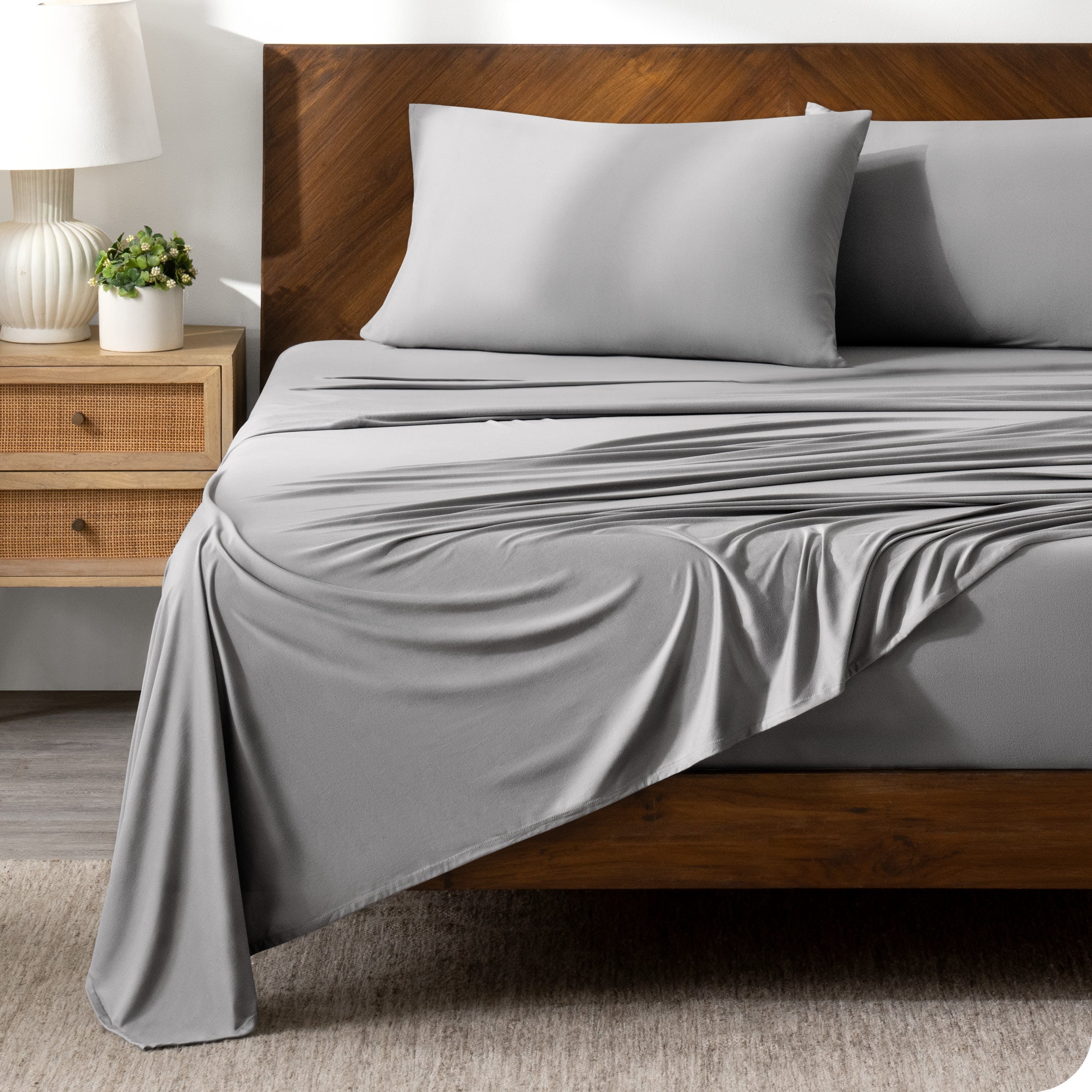 Grey sheet set on a bed with a dark wooden bed frame