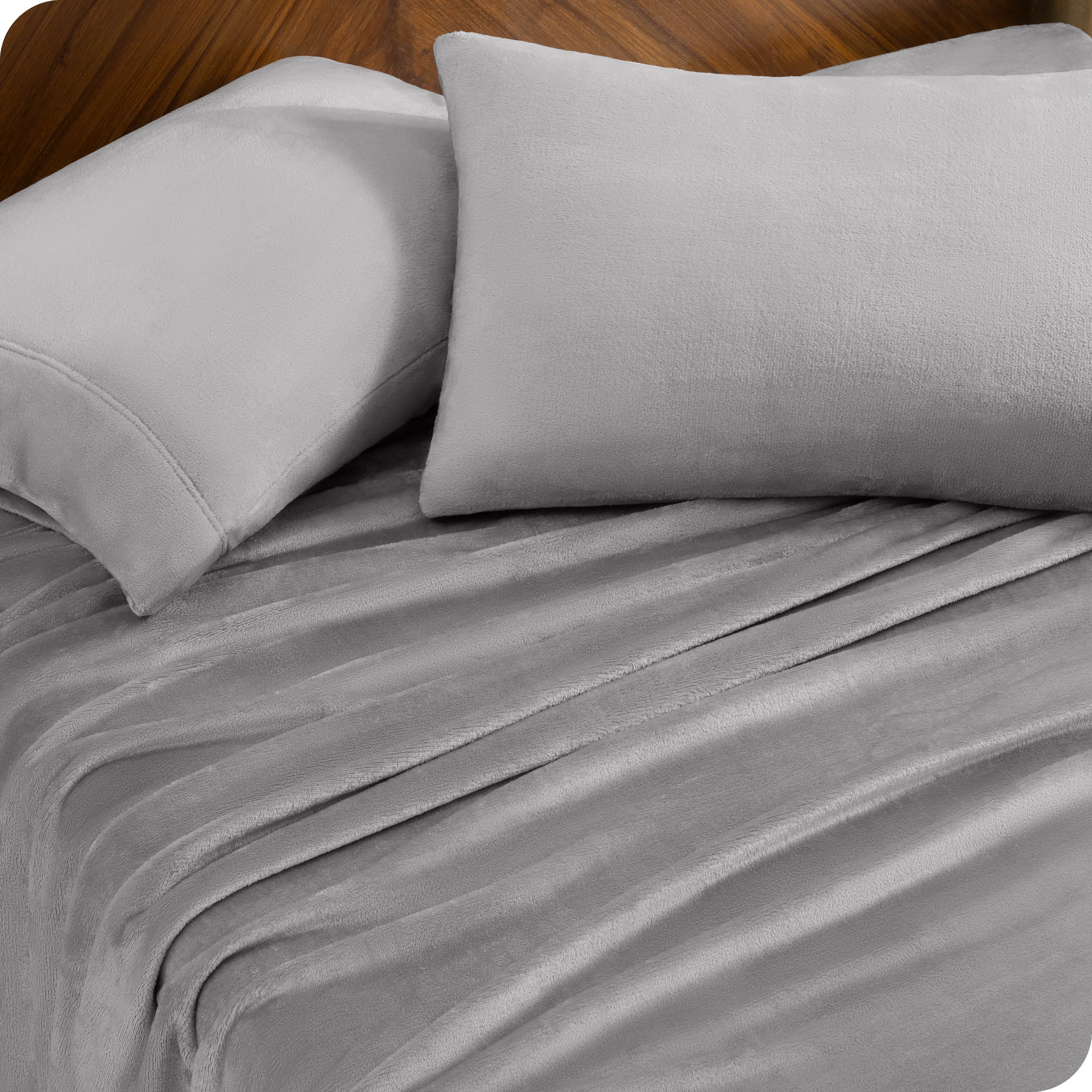 Two pillows with pillowcases on them set on a bed with matching sheets