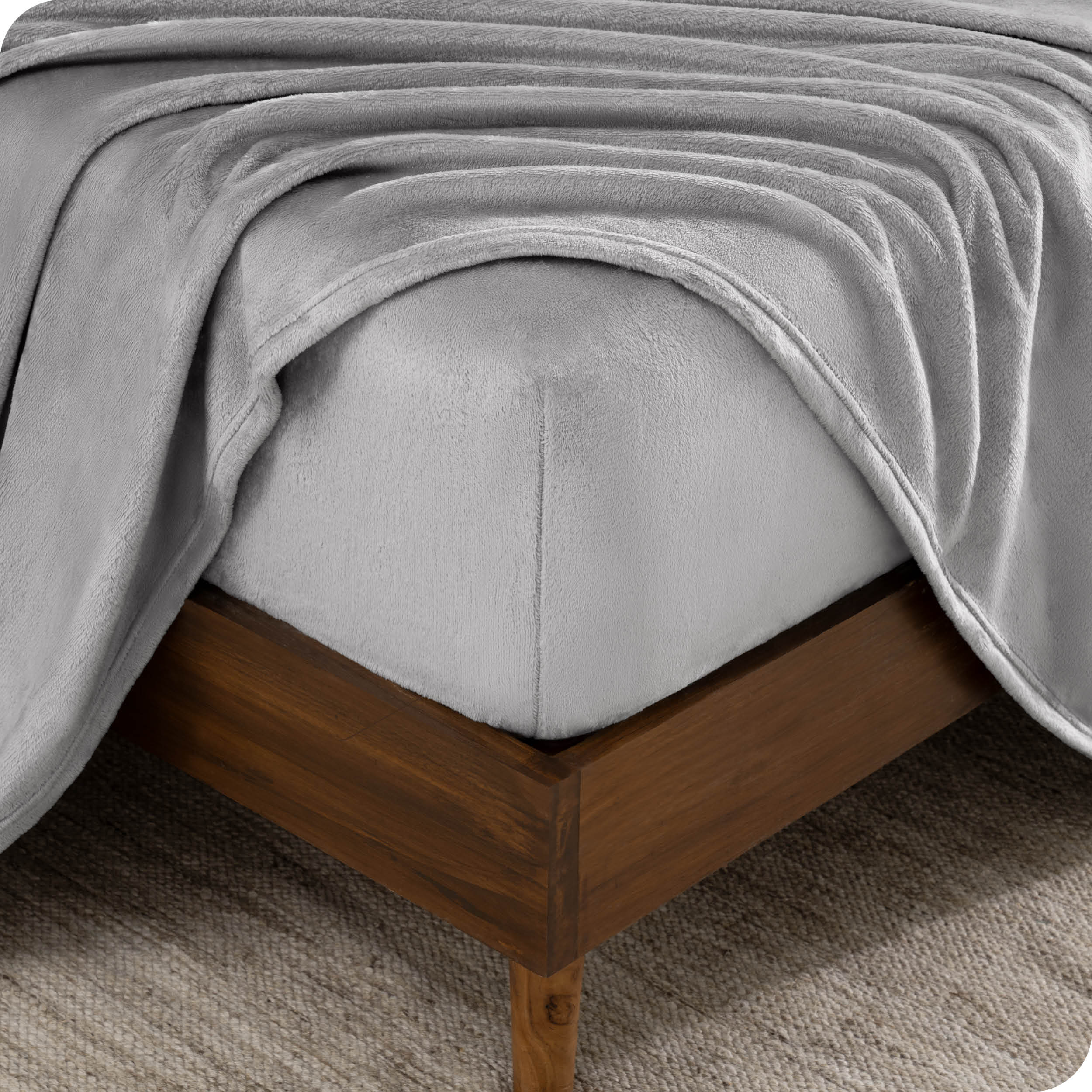 A corner of a mattress with a fitted sheet and a flat sheet on it.