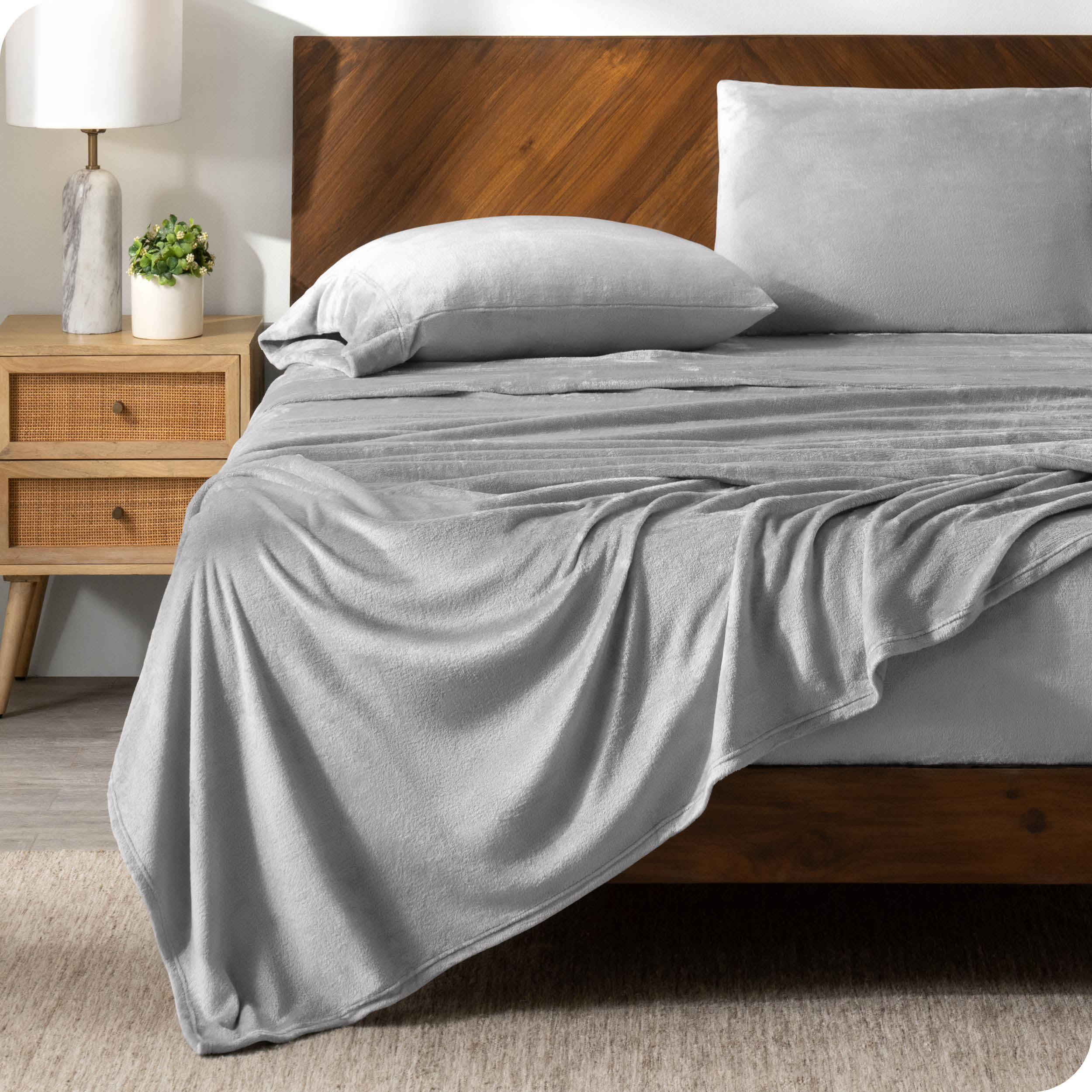 A light grey sheet set on a bed with a wooden bed frame
