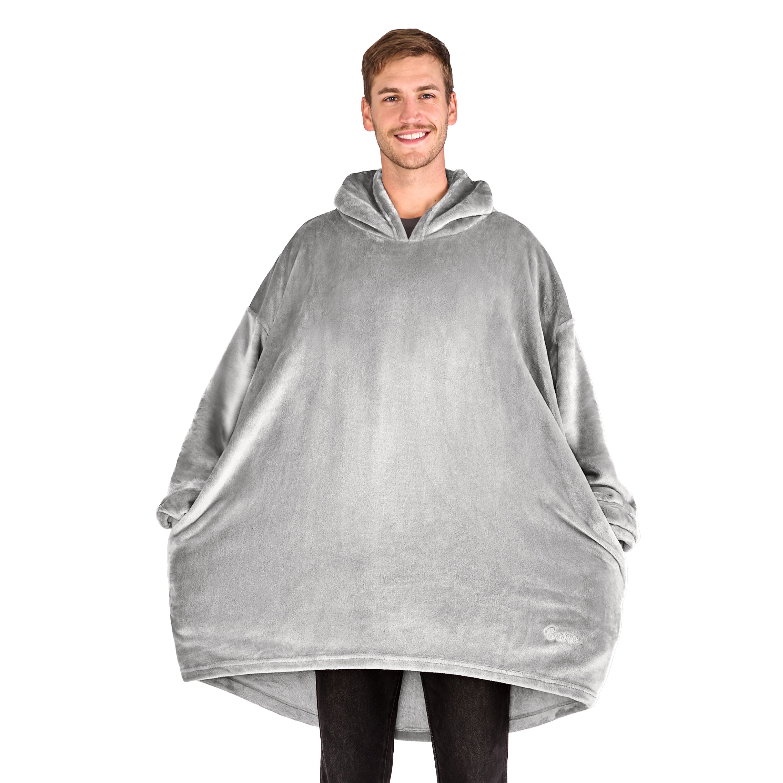 A man has a microplush wearable blanket on and his hands are in the side pockets