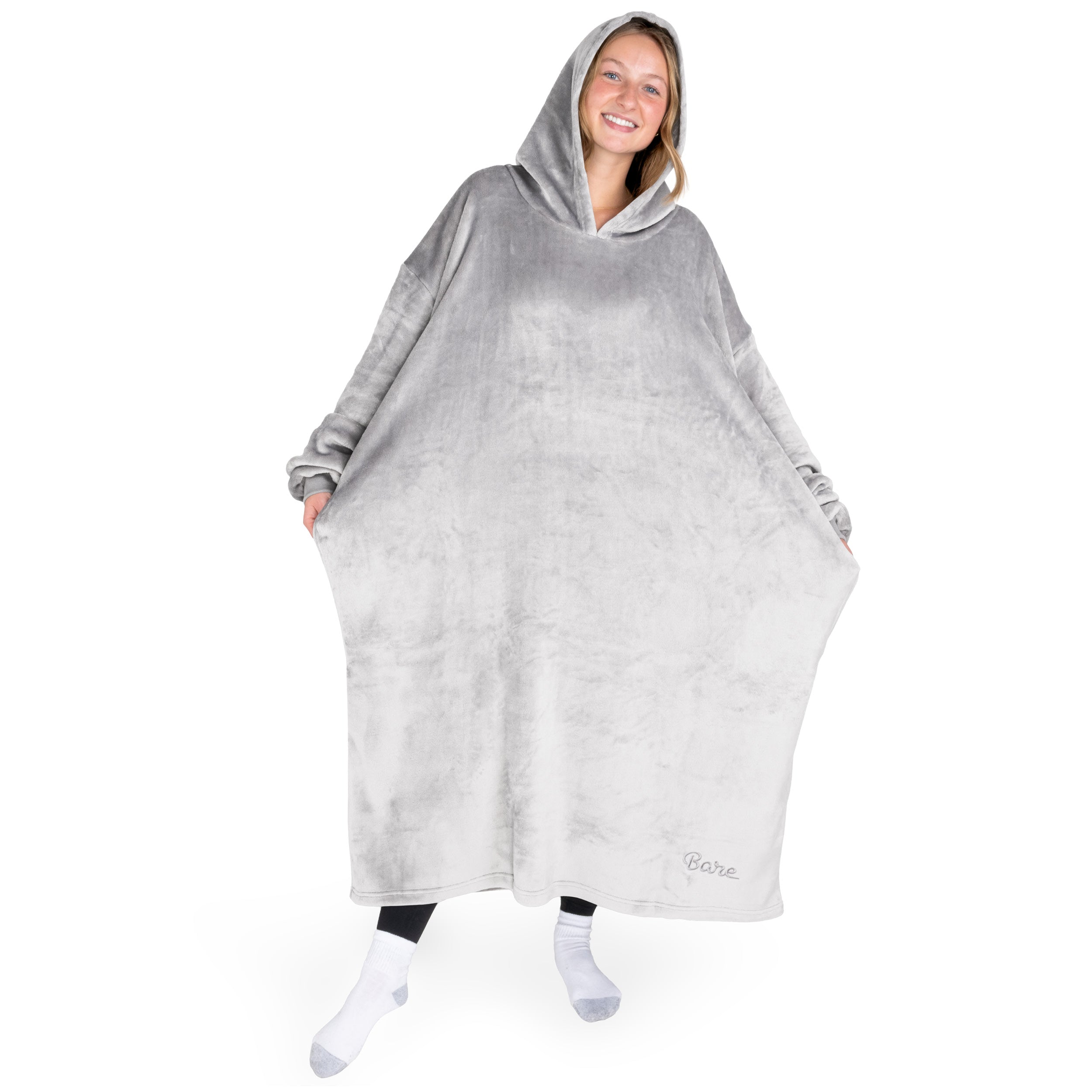 An adult is standing while wearing a long microplush wearable blanket