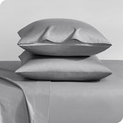 Two sateen pillowcases stacked on a bed