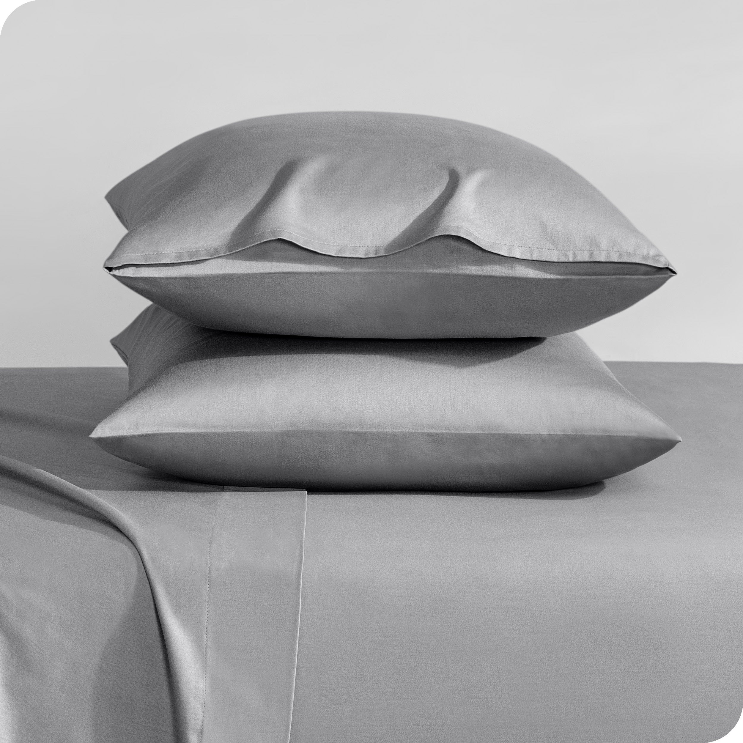 Two sateen pillowcases stacked on a bed