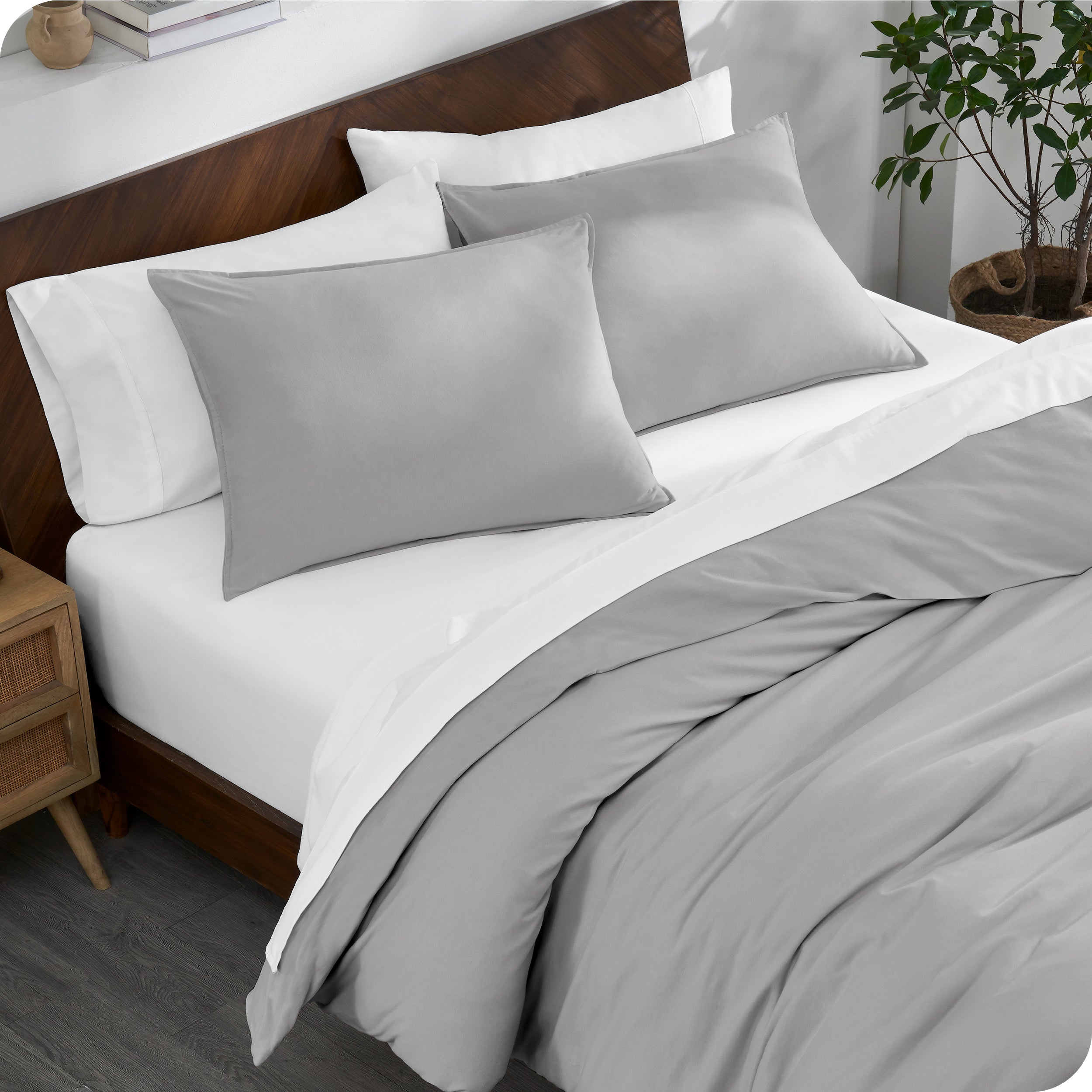 A bed made with an organic jersey duvet cover, pillow sham covered pillows and extra pillows