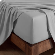 Close up of the corner of a mattress with a fitted sheet and flat sheet on it