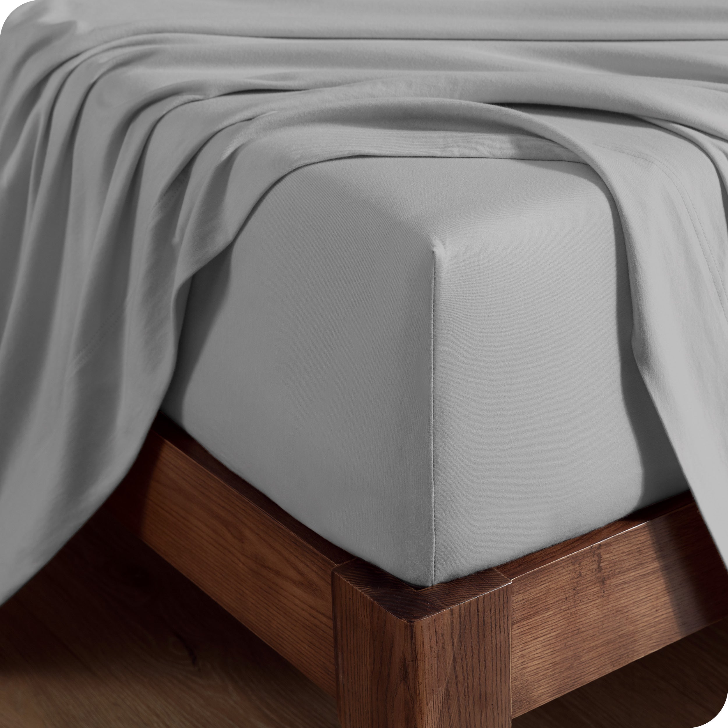 Close up of the corner of a mattress with a fitted sheet and flat sheet on it