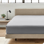 A percale fitted sheet on a bed with table next to it