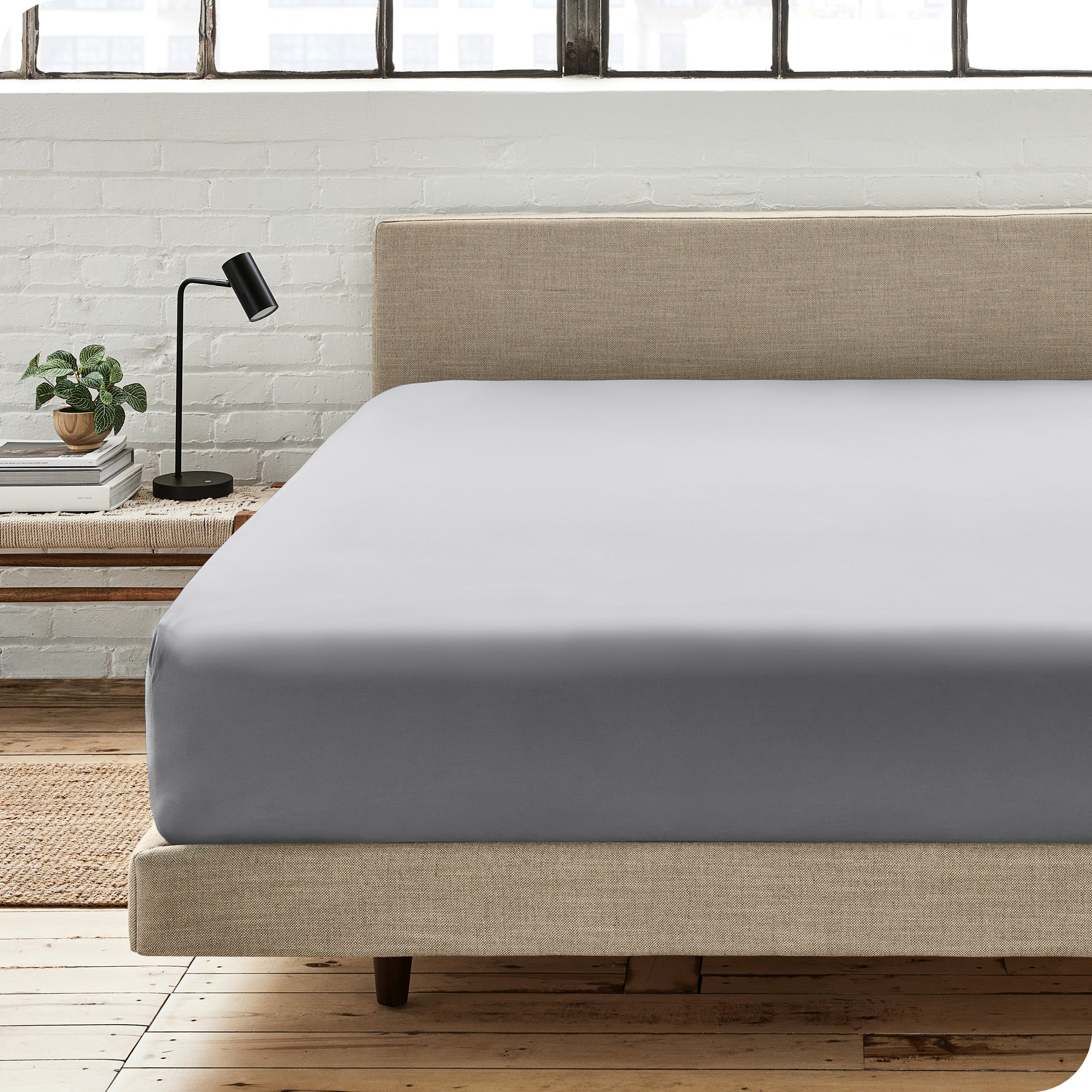 A percale fitted sheet on a bed with table next to it