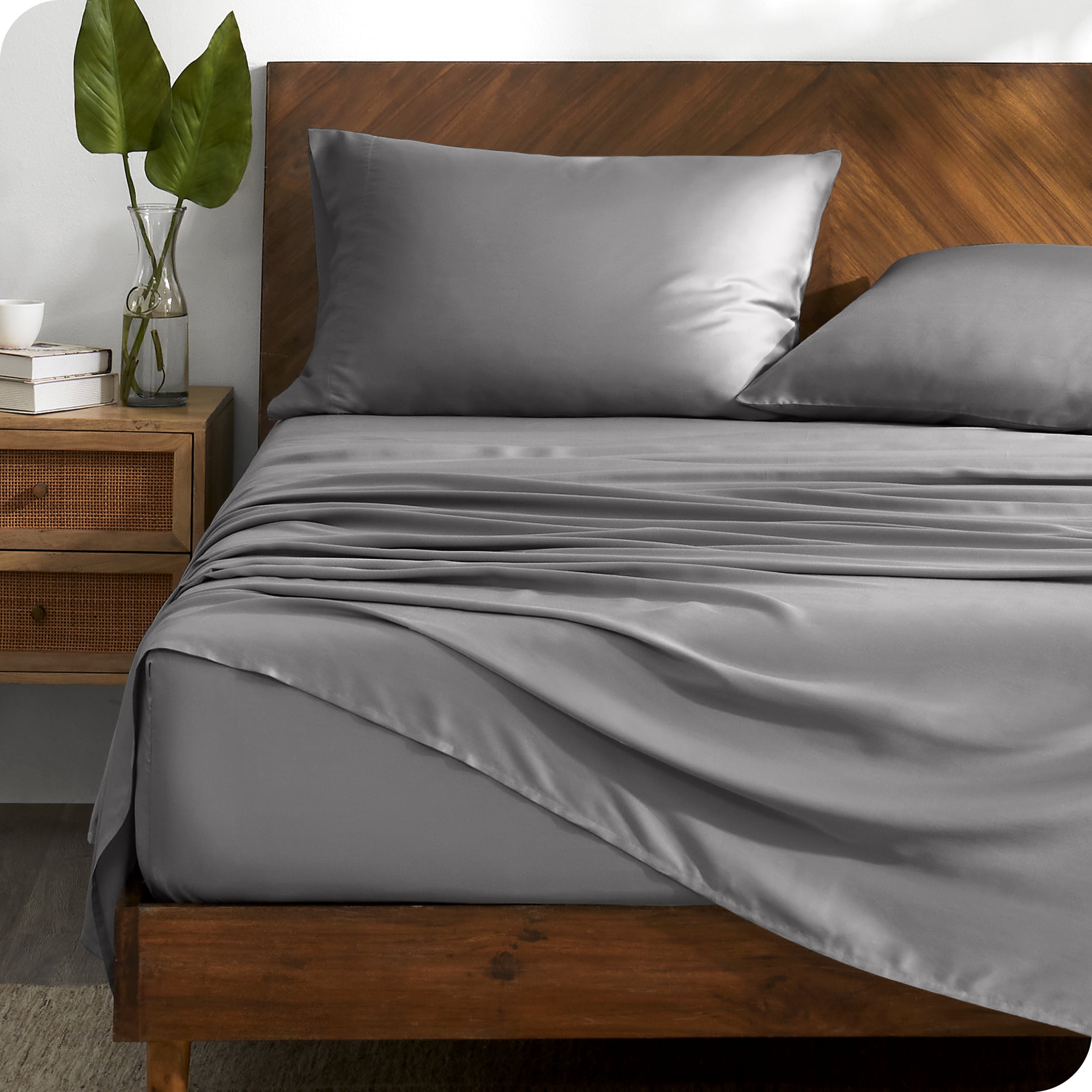 TENCEL™ sheet set on a bed with the flat sheet loosely draped over the top. The mattress is on a wooden bed frame.