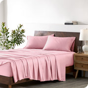 Modern bedroom with a bed against a white wall with a nightstand next to the bed. The bed has bamboo sheets draped over it.
