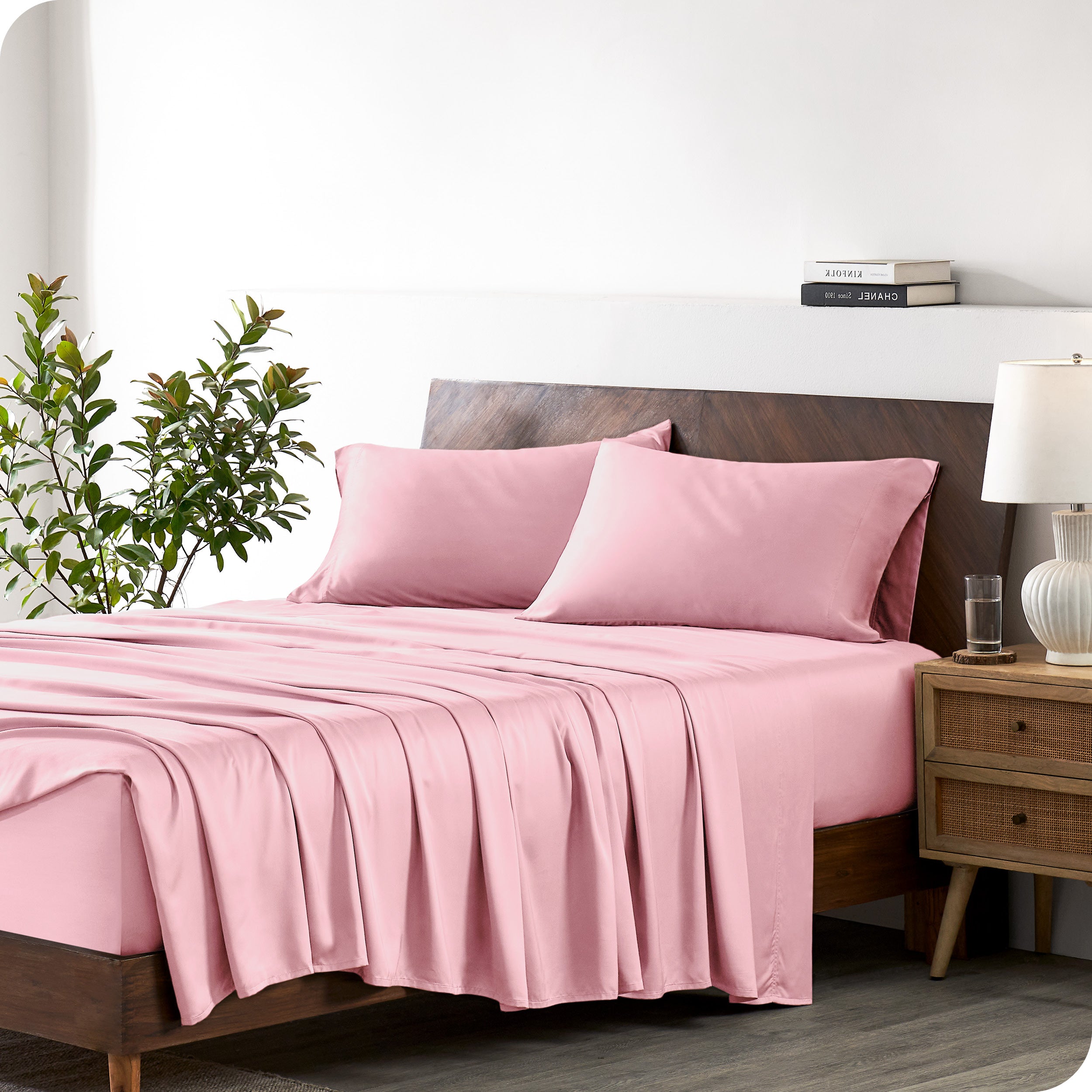Modern bedroom with a bed against a white wall with a nightstand next to the bed. The bed has bamboo sheets draped over it.