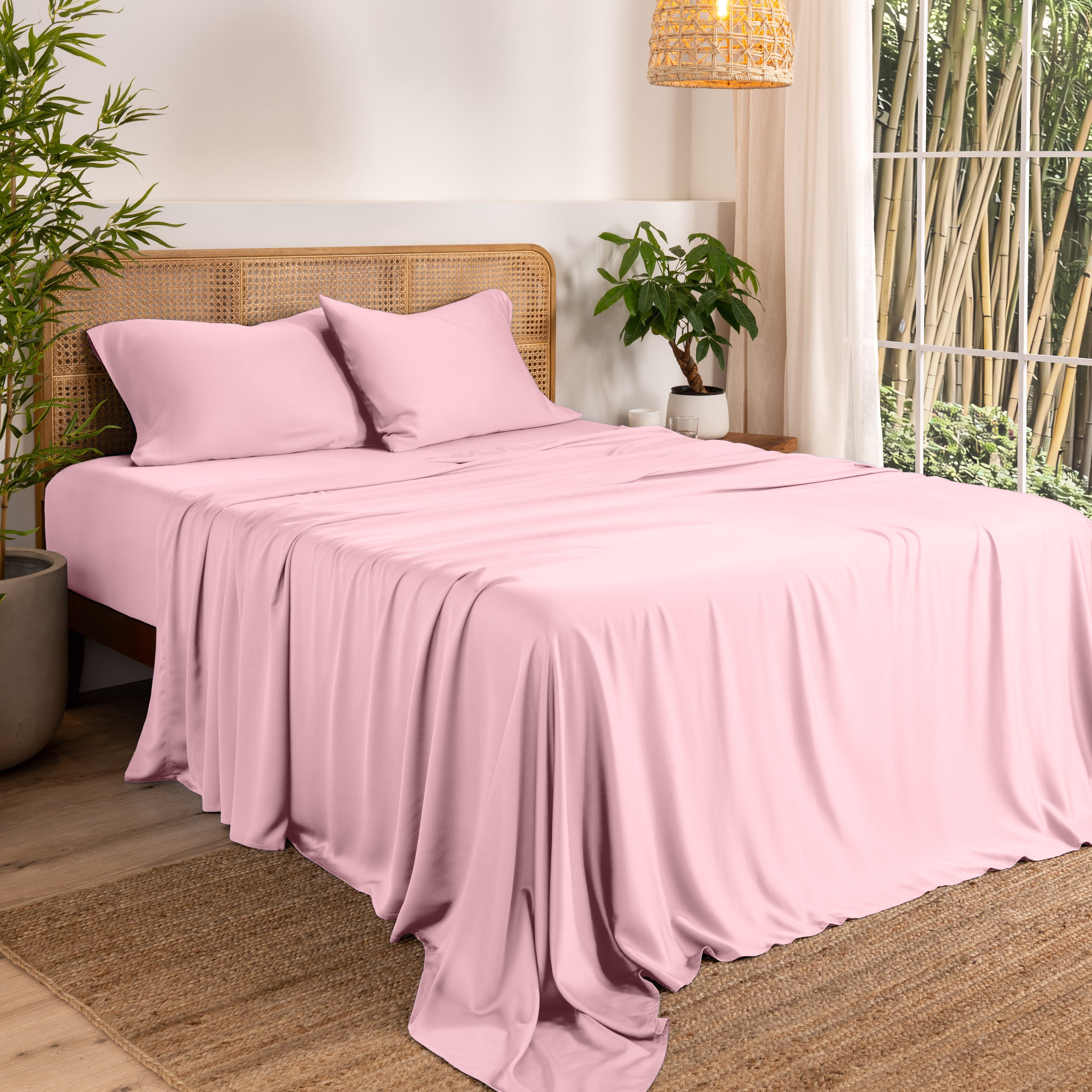 Bamboo sheets on a bed in a bedroom with plants and a window.