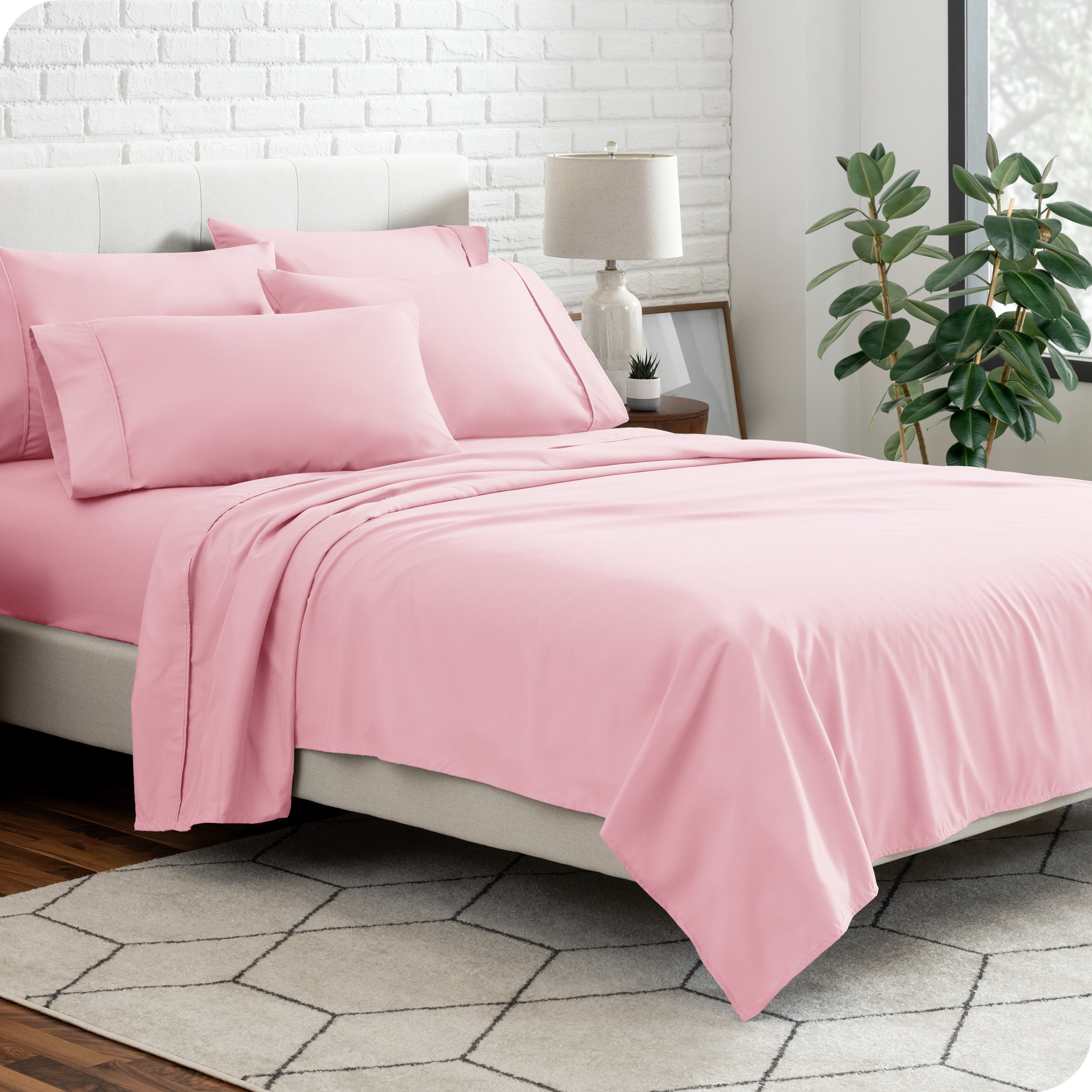 A bedroom setting with a bed made with the microfiber bed sheets and four pillows.