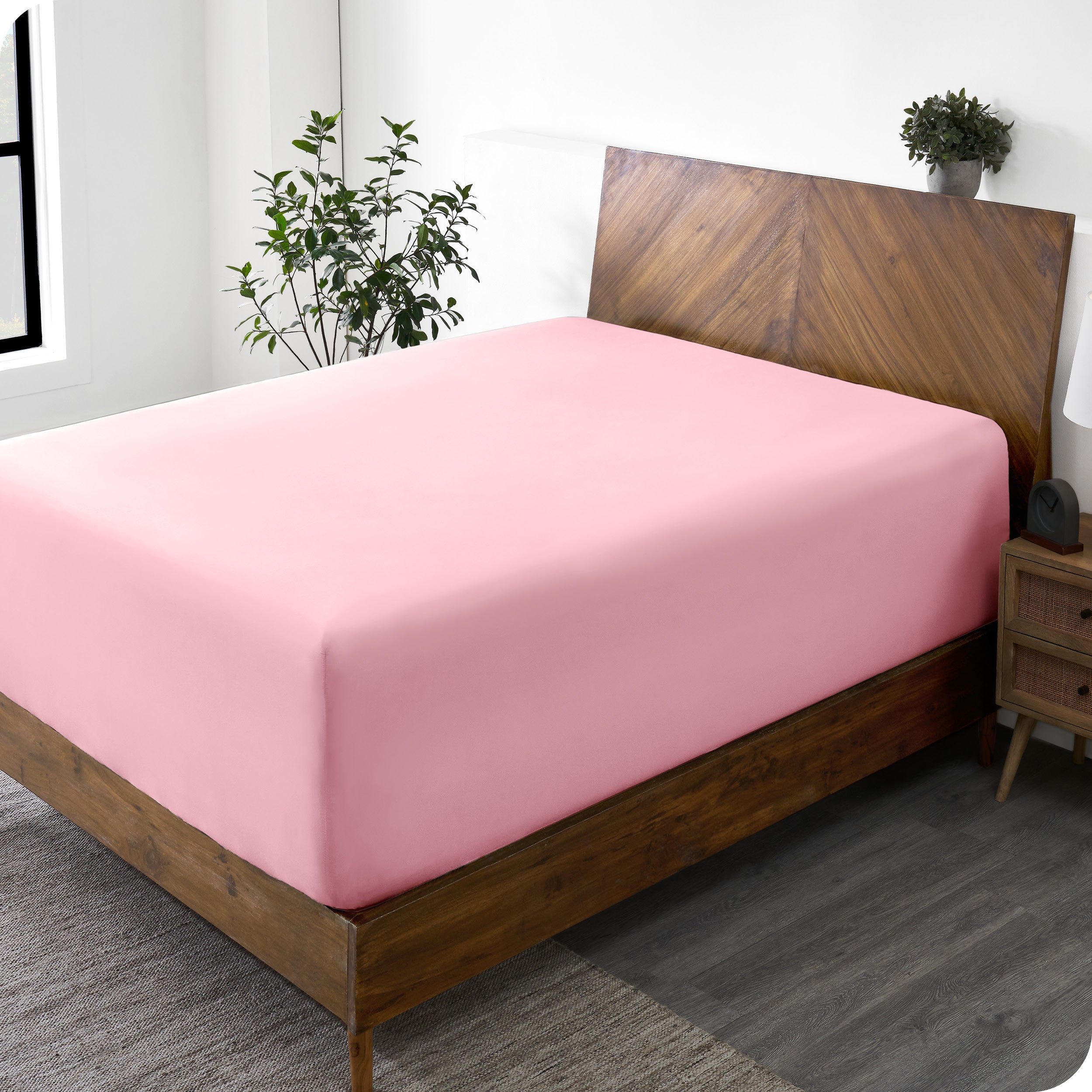 A wide corner view of a modern bed made with a microfiber fitted sheet on the mattress. 