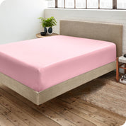 Corner view of a modern bed with a microfiber fitted sheet on the mattress. 