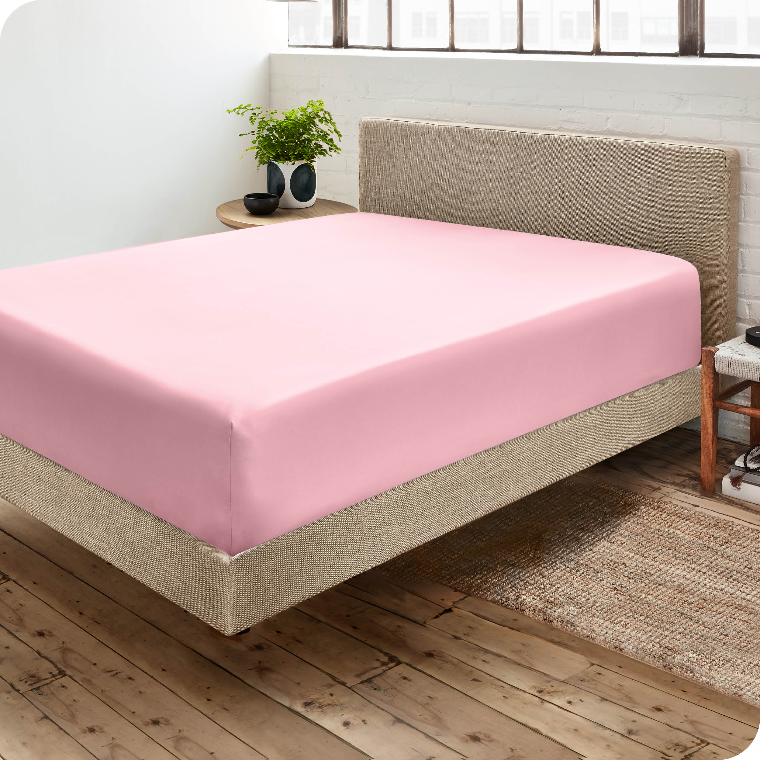 Corner view of a modern bed with a microfiber fitted sheet on the mattress. 