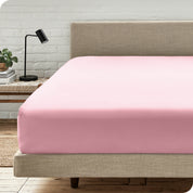 A bed with a microfiber fitted sheet on the mattress. 