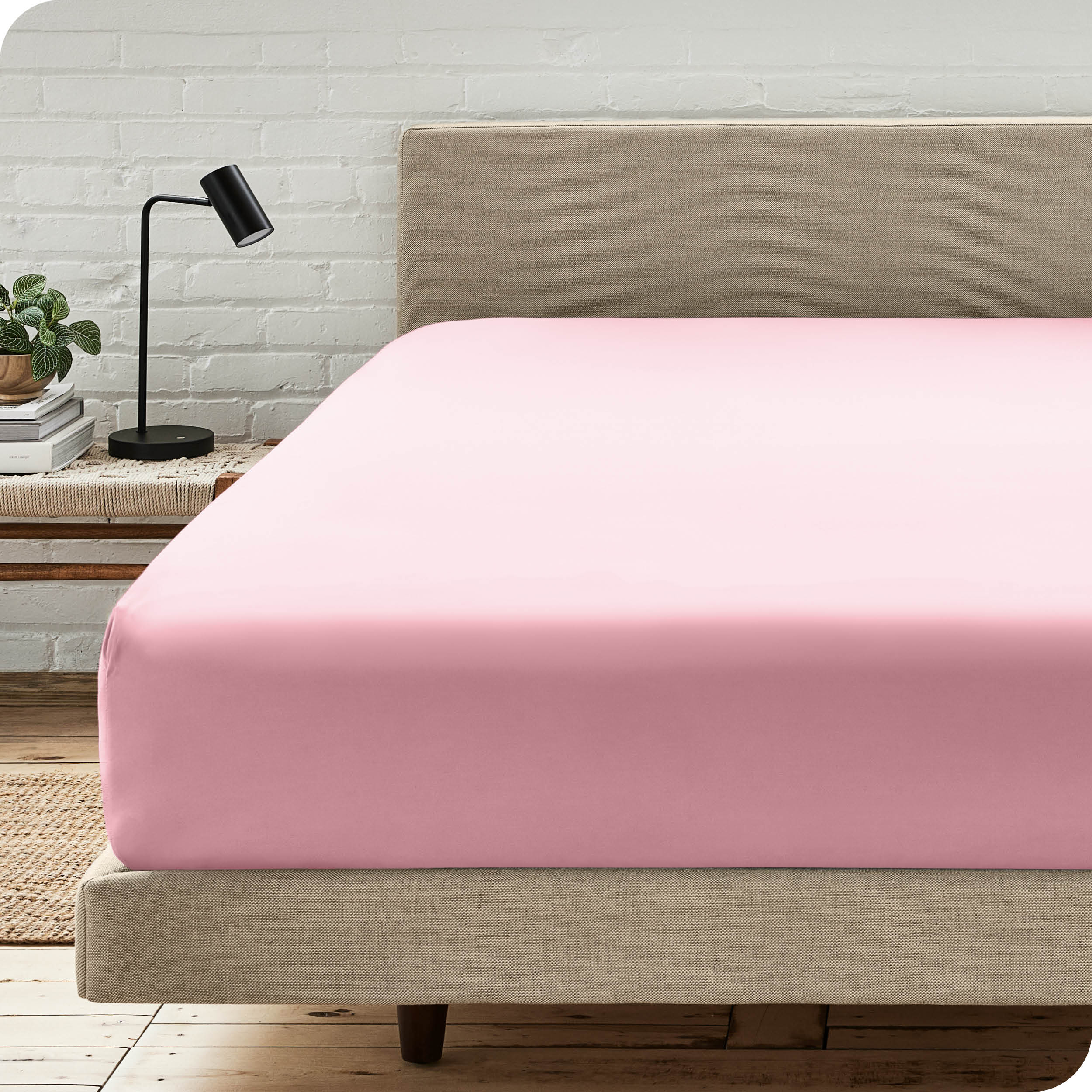 A bed with a microfiber fitted sheet on the mattress. 
