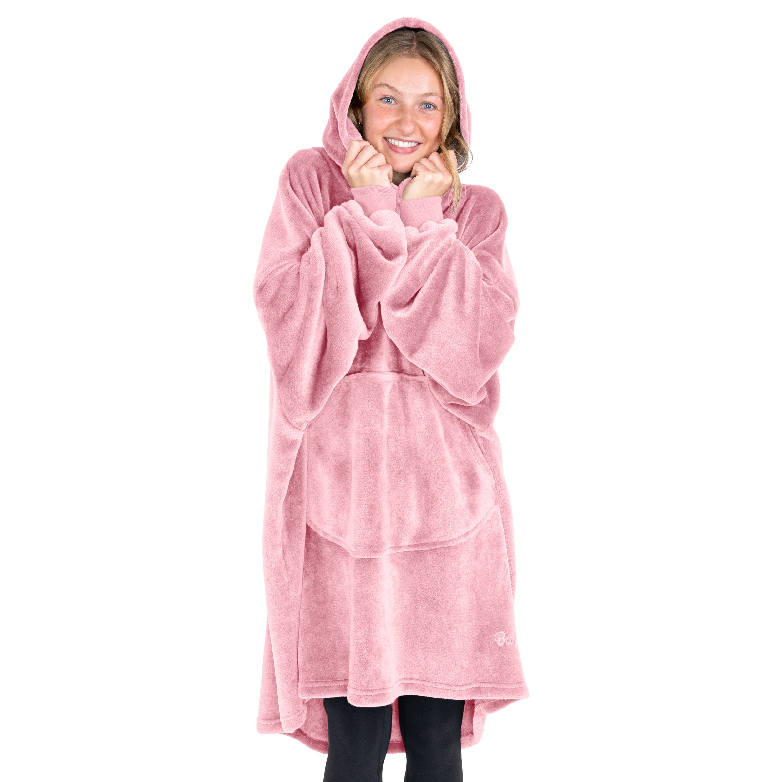 A woman is snuggled up in a hooded microplush wearable blanket