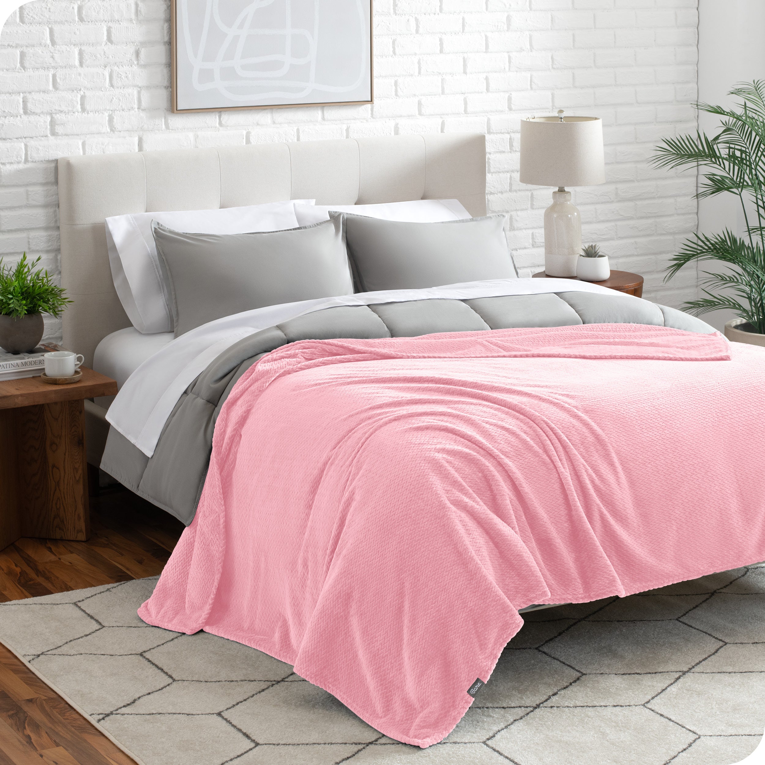 A textured microplush blanket is draped over a bed made with grey duvet set