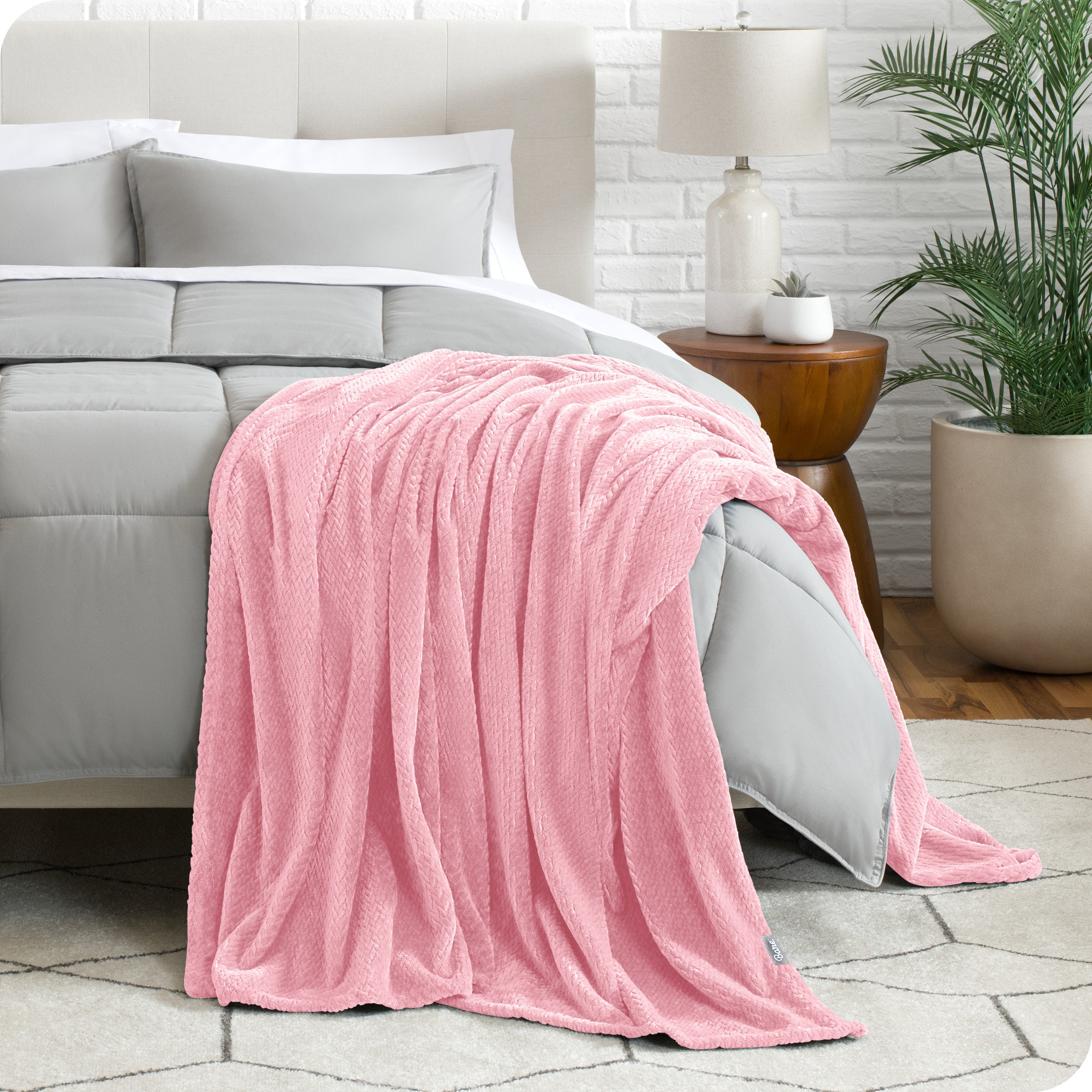 A textured microplush blanket is hanging over the corner of a bed