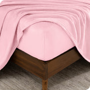 A corner of a mattress with a fitted sheet and a flat sheet on it.