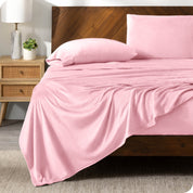 A light pink sheet set on a bed with a wooden bed frame