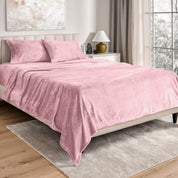 Sheets and matching pillowcases on a bed in a bedroom with a lamp and window in the background.