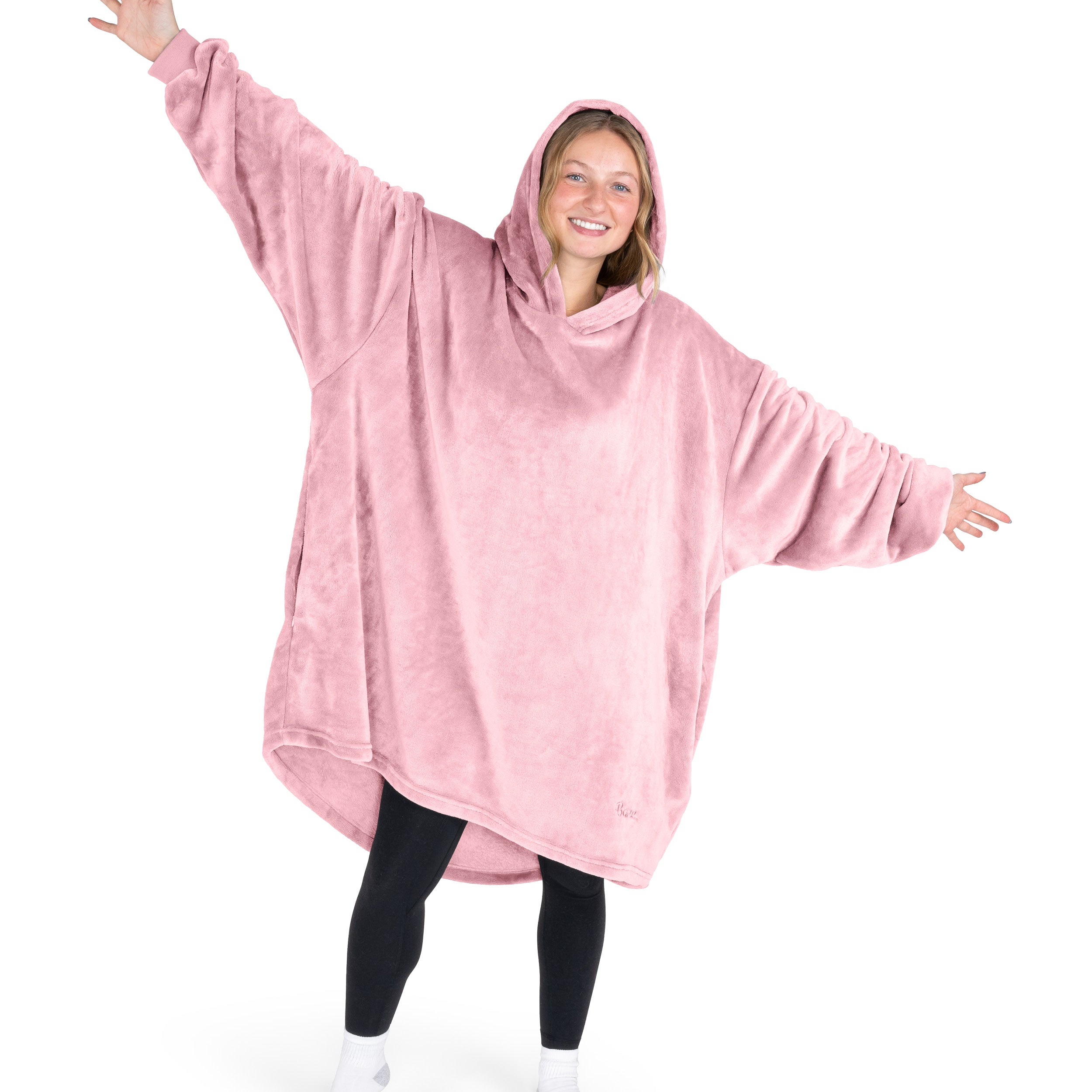 A woman is standing with her arms stretched out and has a hooded wearable blanket on