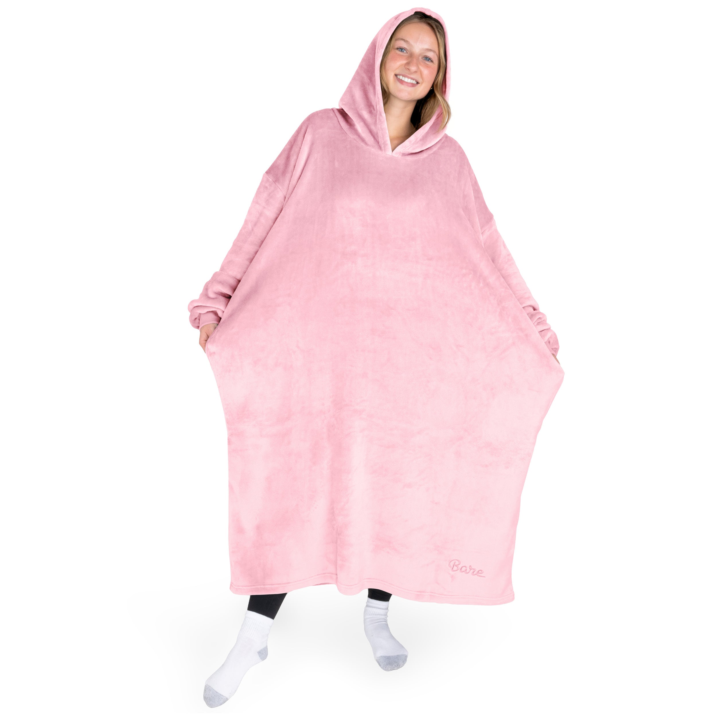 An adult is standing while wearing a long microplush wearable blanket