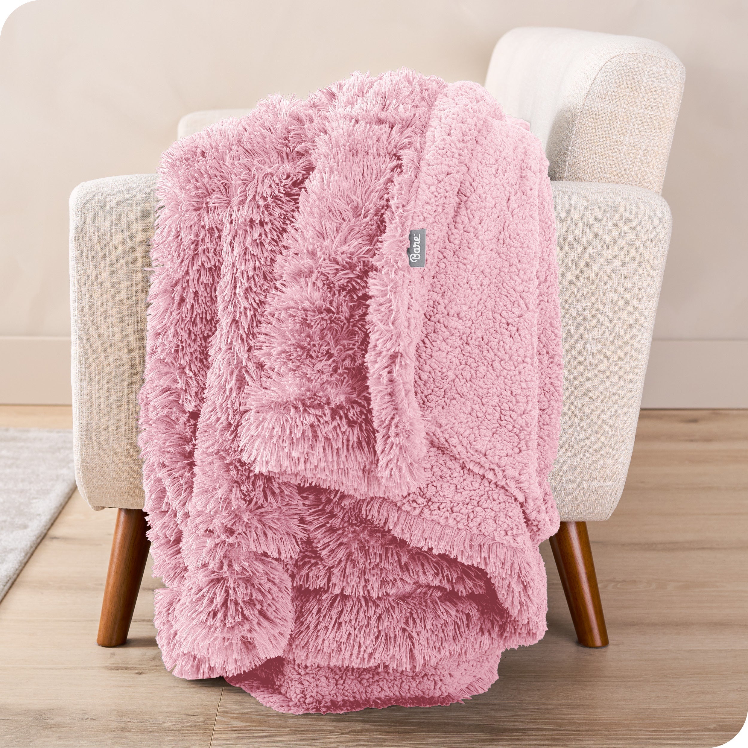 A shaggy faux fur blanket draped over the arm of a chair