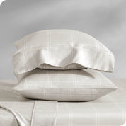 Two pillowcases on pillows stacked on a bed with matching sheets