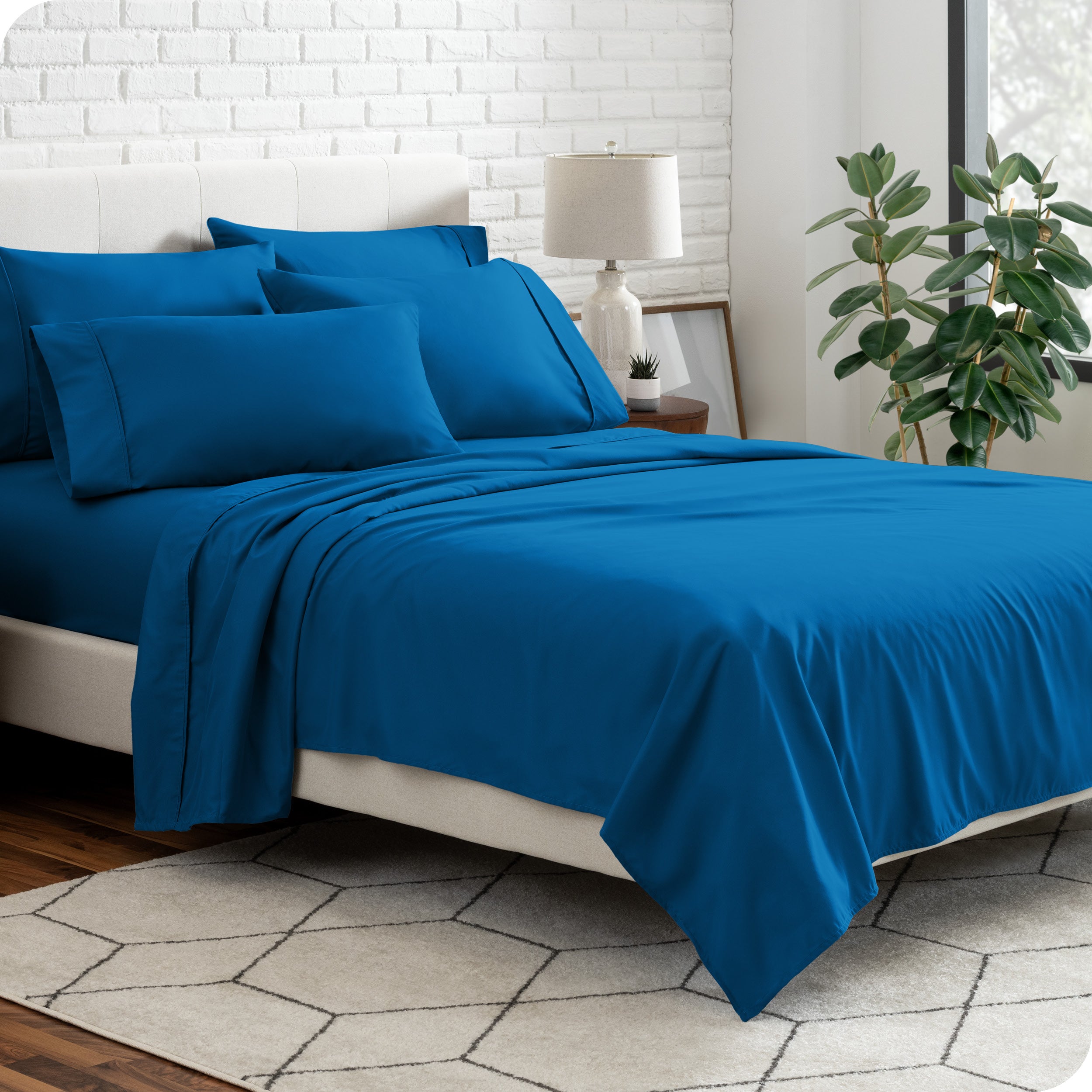 A bedroom setting with a bed made with the microfiber bed sheets and four pillows.