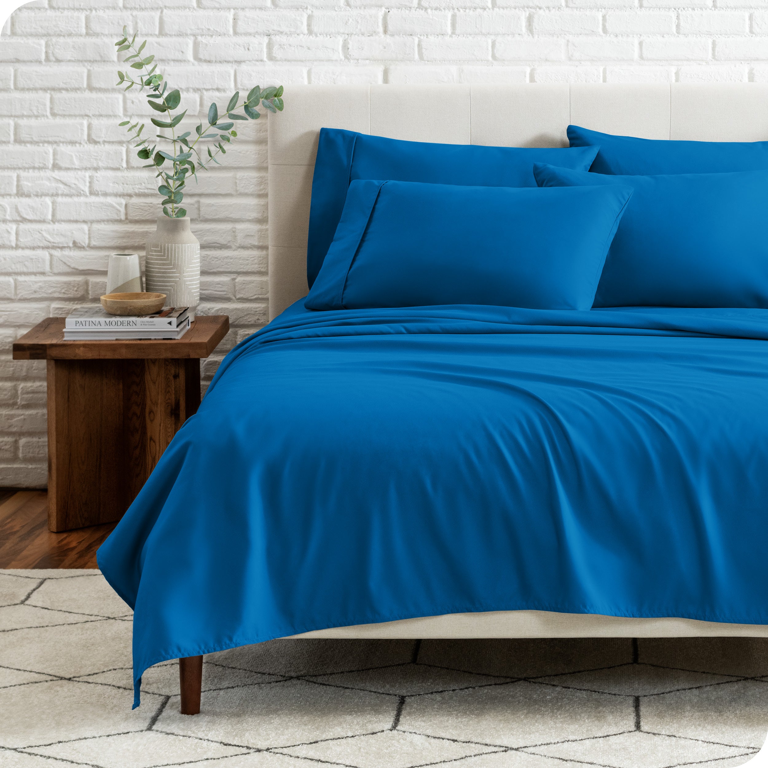 End view of a modern bed with the microfiber sheets on the bed with four pillows.