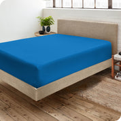 Corner view of a modern bed with a microfiber fitted sheet on the mattress. 