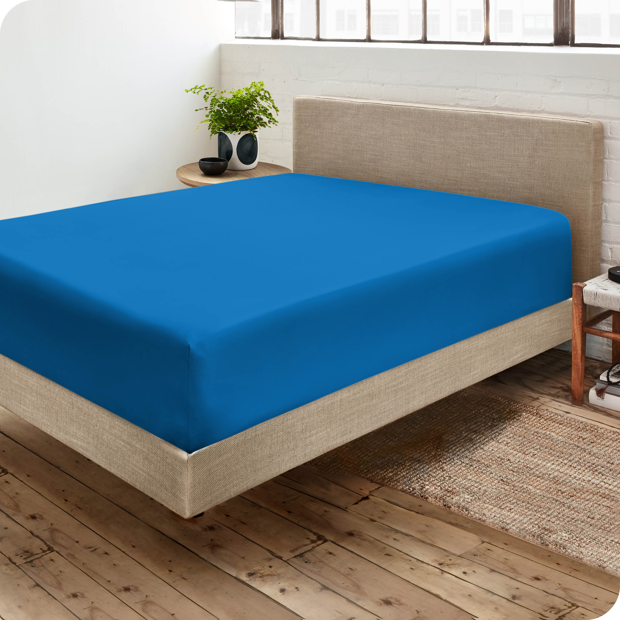 Corner view of a modern bed with a microfiber fitted sheet on the mattress. 