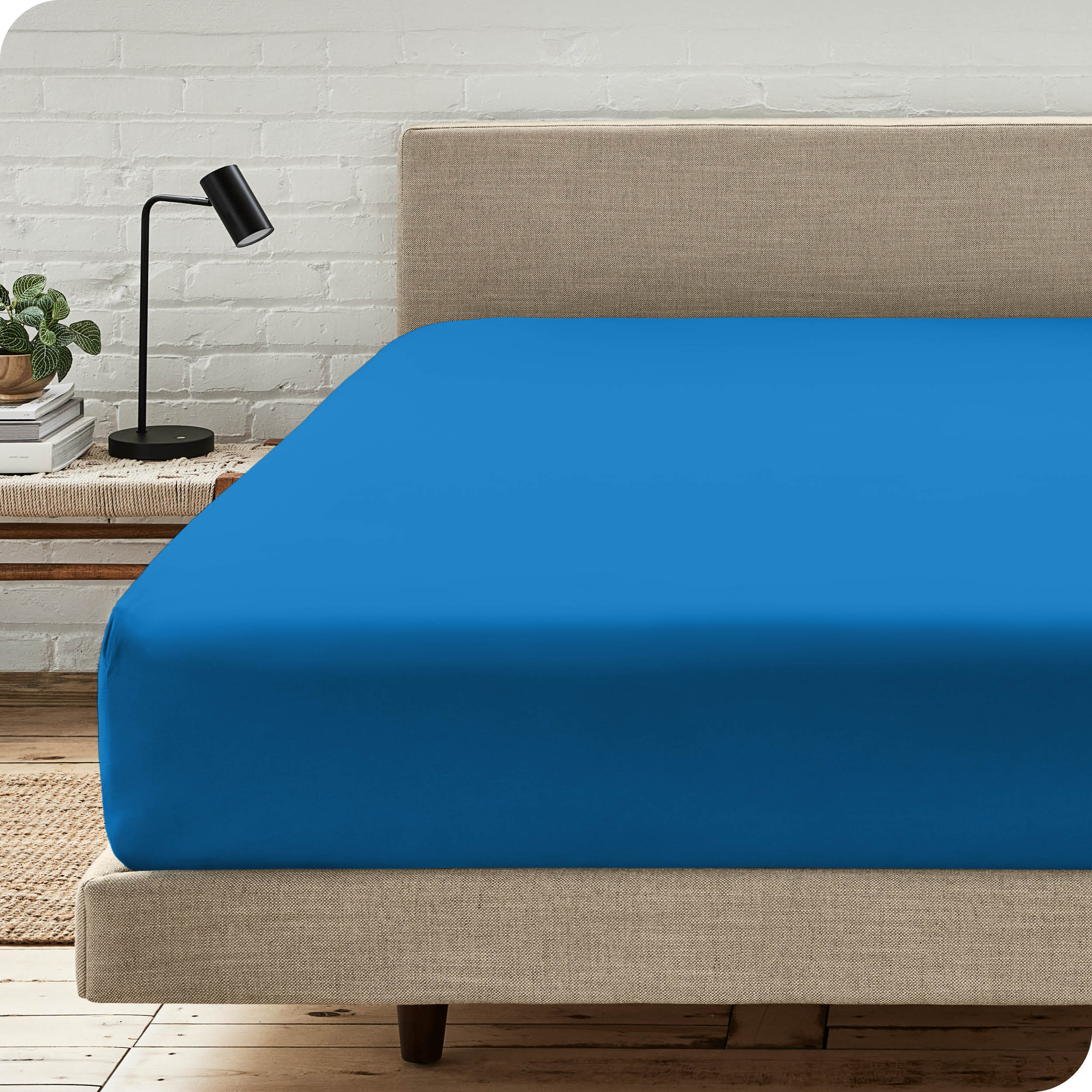 A bed with a microfiber fitted sheet on the mattress. 