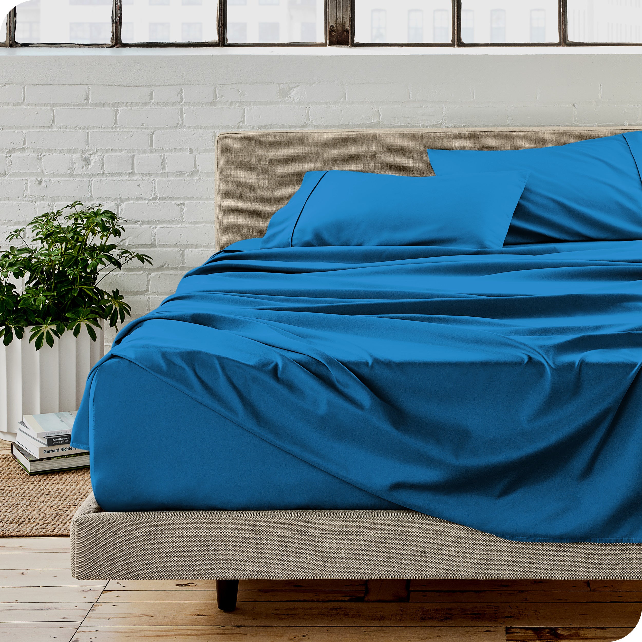 Microfiber sheets on a bed with a brick wall behind it