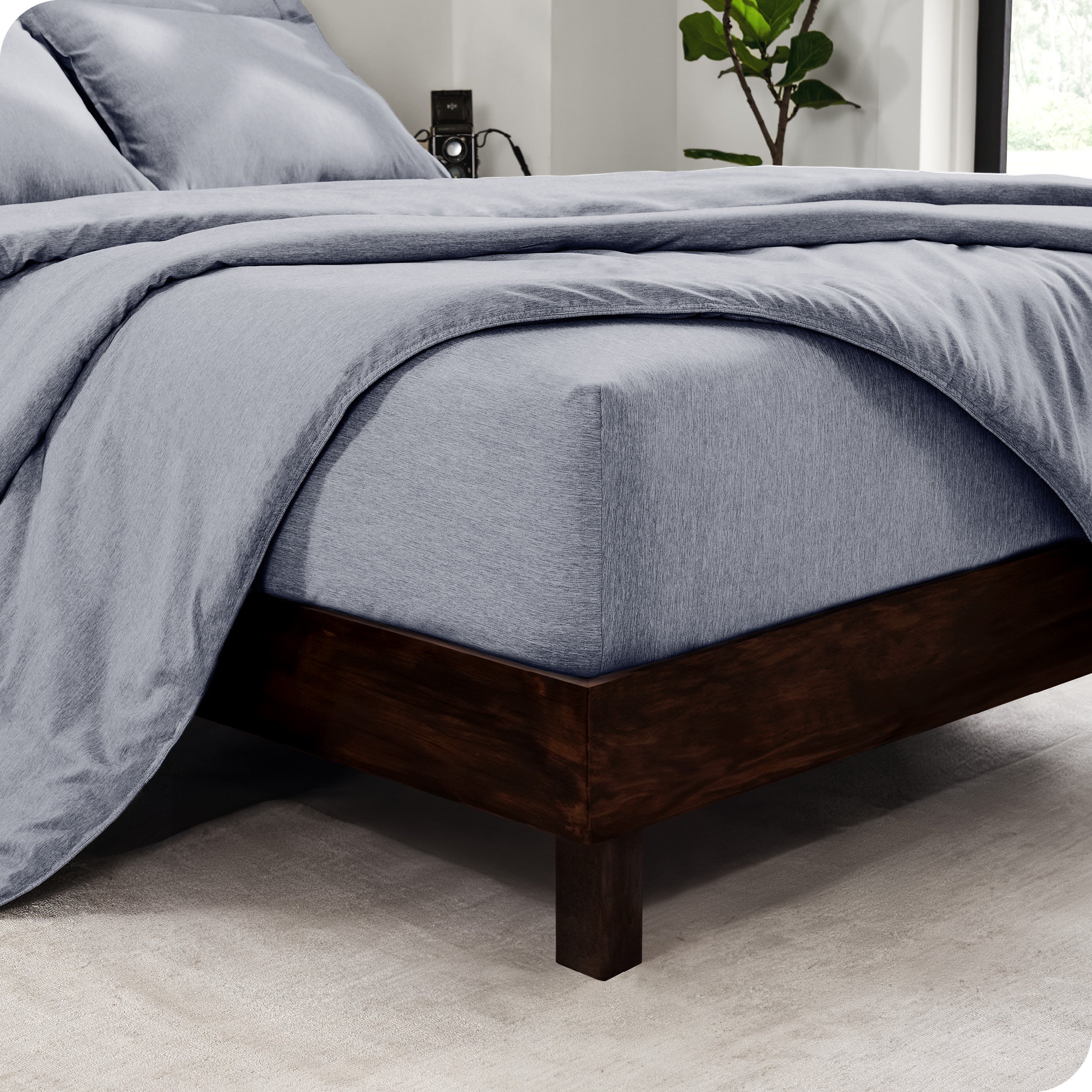 The corner of a mattress with a fitted sheet and comforter on it