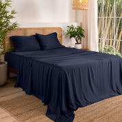 Bamboo sheets on a bed in a bedroom with plants and a window.