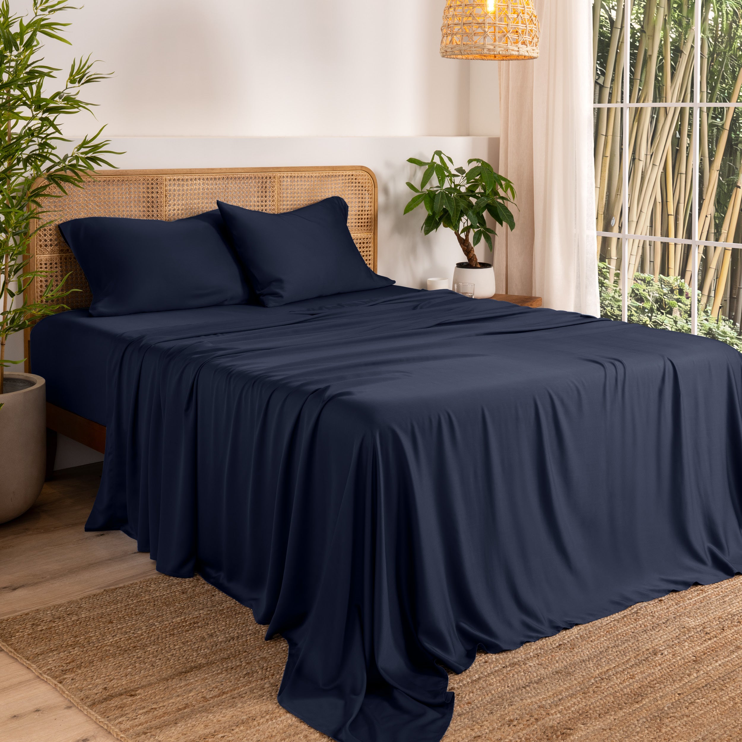 Bamboo sheets on a bed in a bedroom with plants and a window.