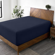 A wide corner view of a modern bed made with a microfiber fitted sheet on the mattress. 