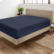 Corner view of a modern bed with a microfiber fitted sheet on the mattress. 