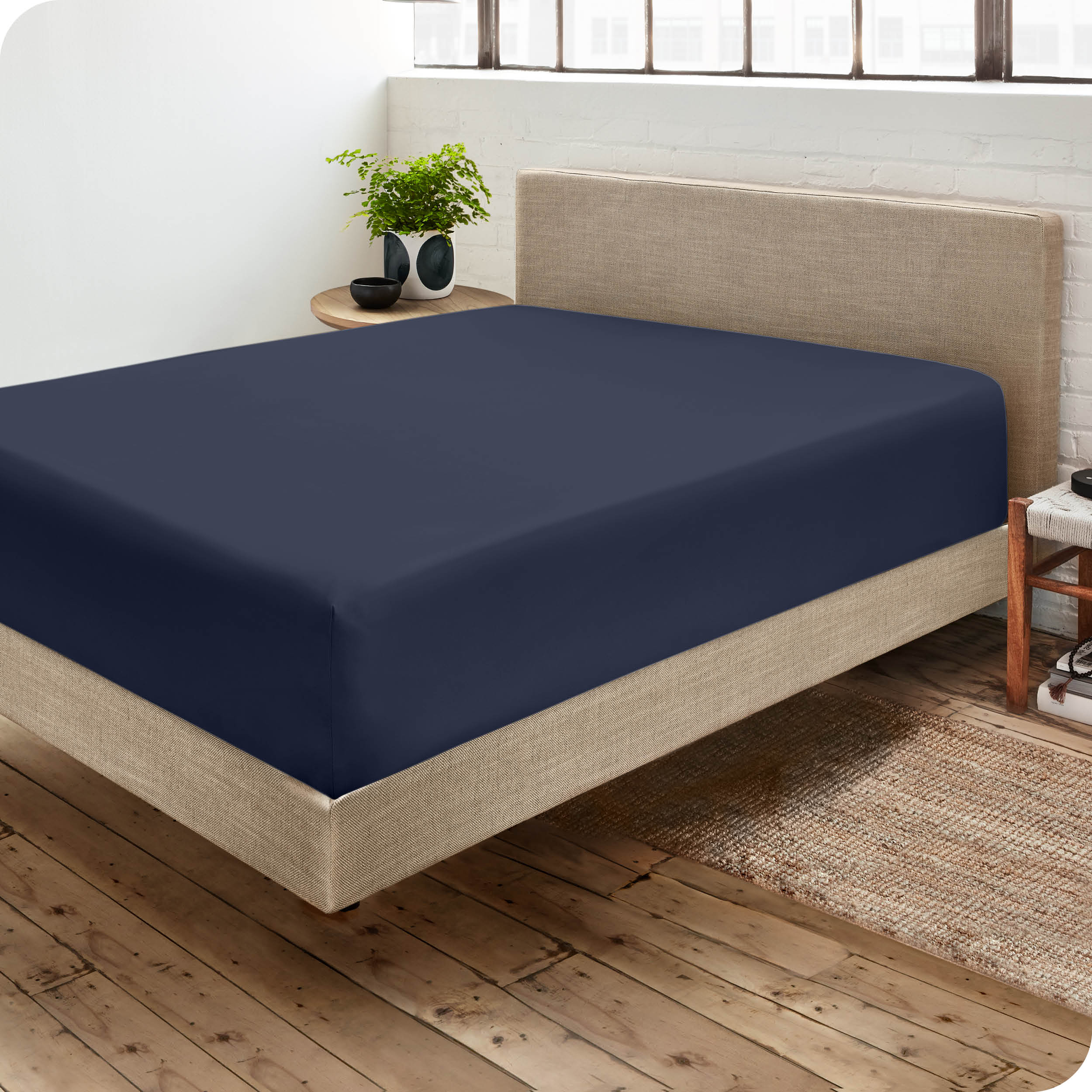 Corner view of a modern bed with a microfiber fitted sheet on the mattress. 
