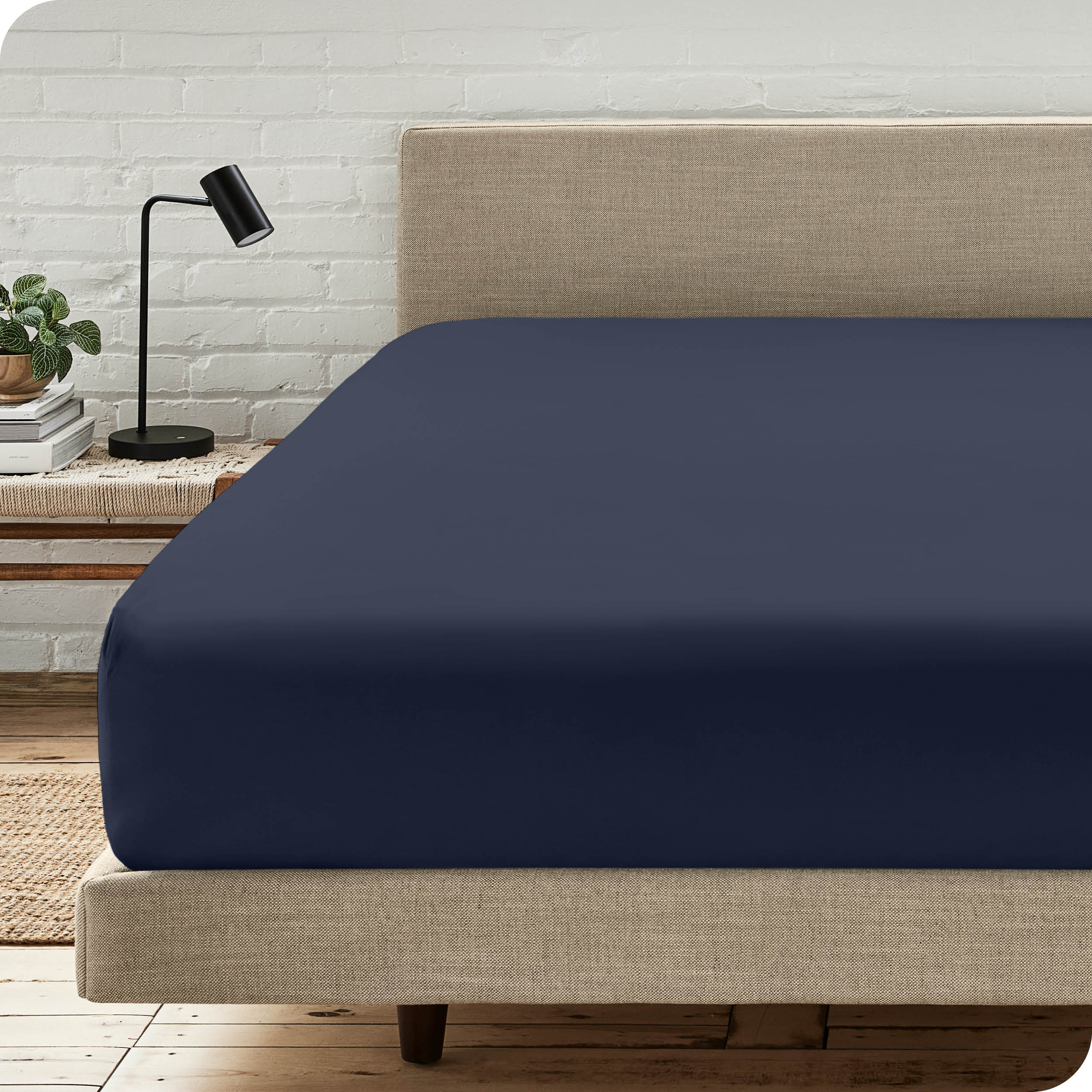 A bed with a microfiber fitted sheet on the mattress. 