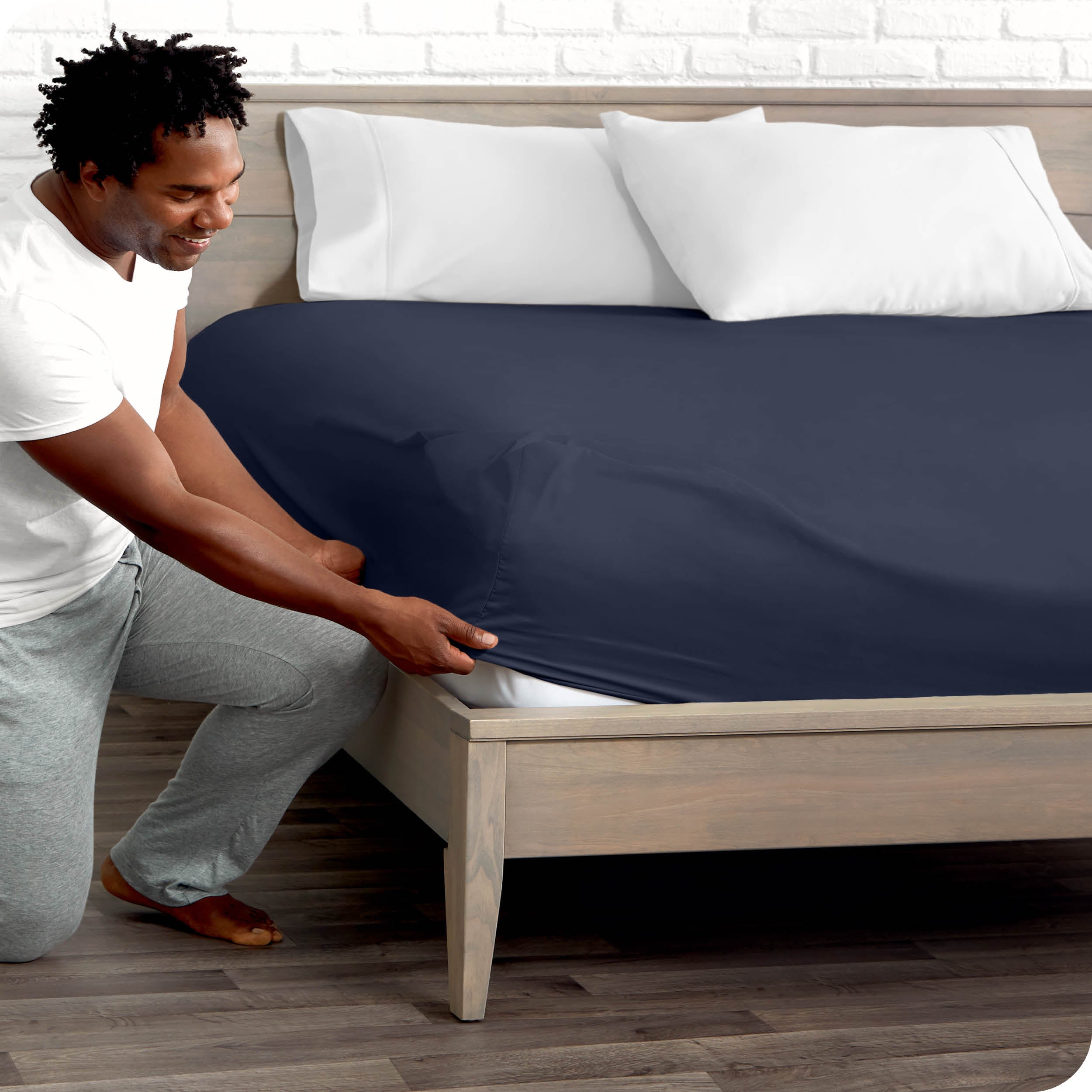 A man putting the microfiber fitted sheet on a mattress. 