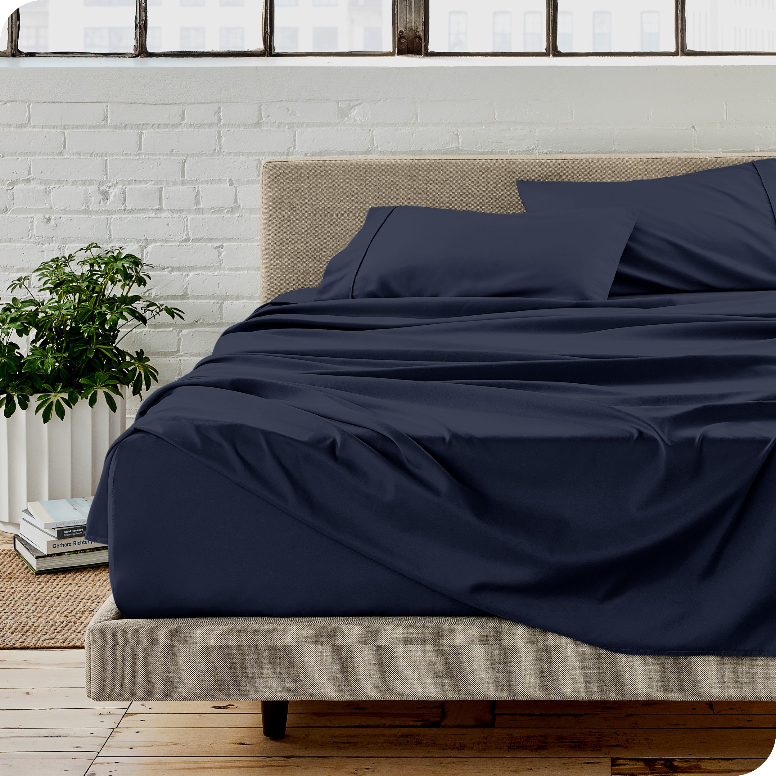 Microfiber sheets on a bed with a brick wall behind it