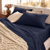 Neatly made bed with pillows and a beige blanket in a bright room.