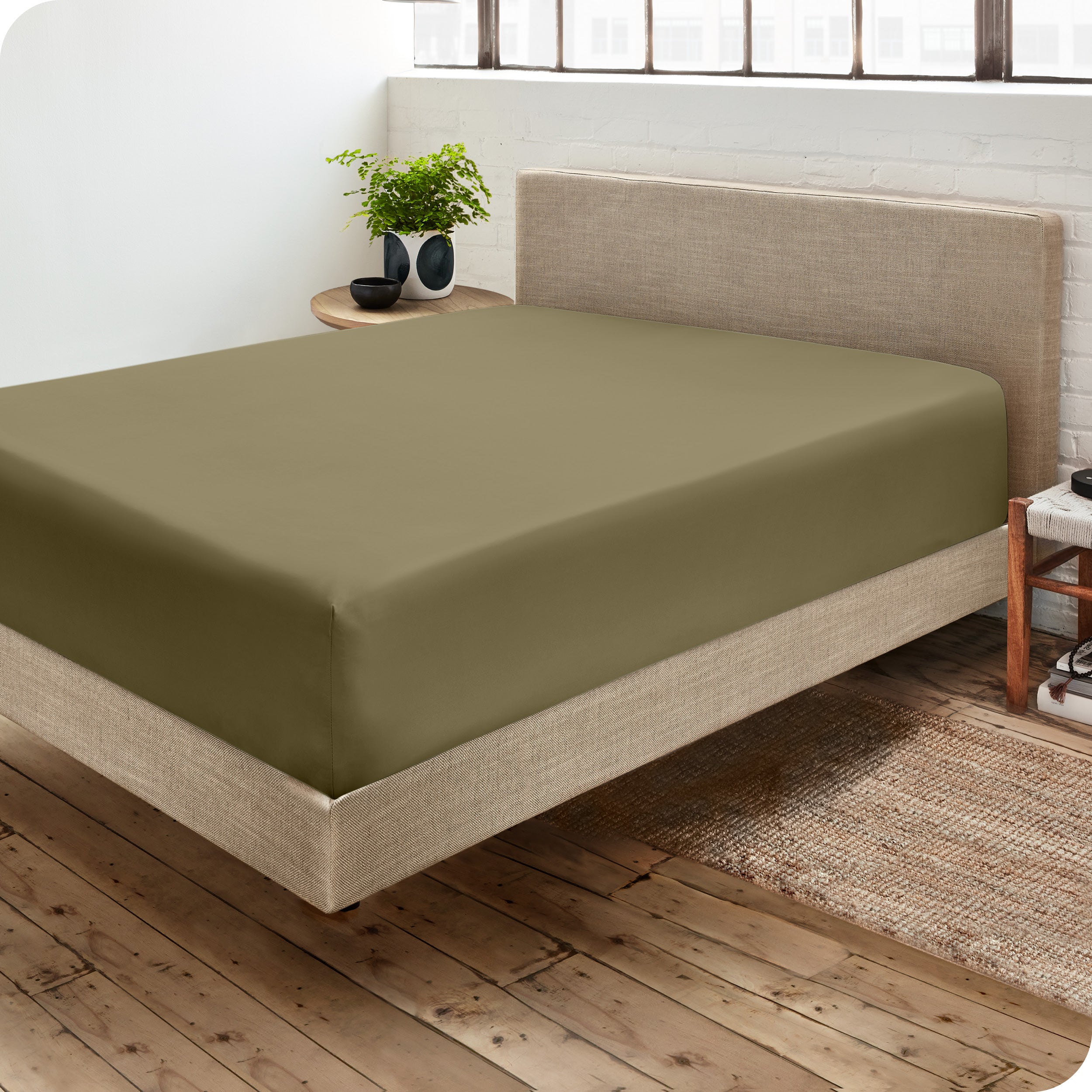 Corner view of a modern bed with a microfiber fitted sheet on the mattress. 
